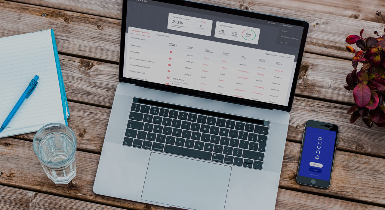 The Phyn Dashboard on a laptop sitting on a table next to a phone showing the Phyn app